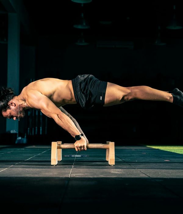 Man performing a controlled core strength exercise in a dark gym.